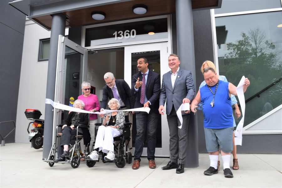 </who> In the centre of the group, BC Housing Minister Ravi Kahlon and Kelowna Mayor Tom Dyas cut the ribbon to officially open Hadgraft Wilson Place.