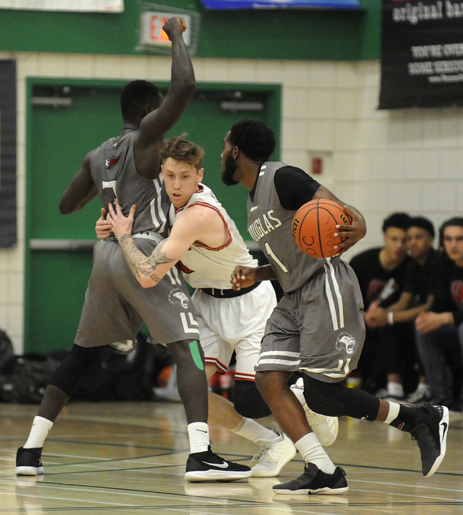 <who>Photo Credit: Lorne White/KelownaNow </who>Jeff Tubbs of the OC Coyotes attempts to squeeze through a pair of Royals on Friday at Immaculata.