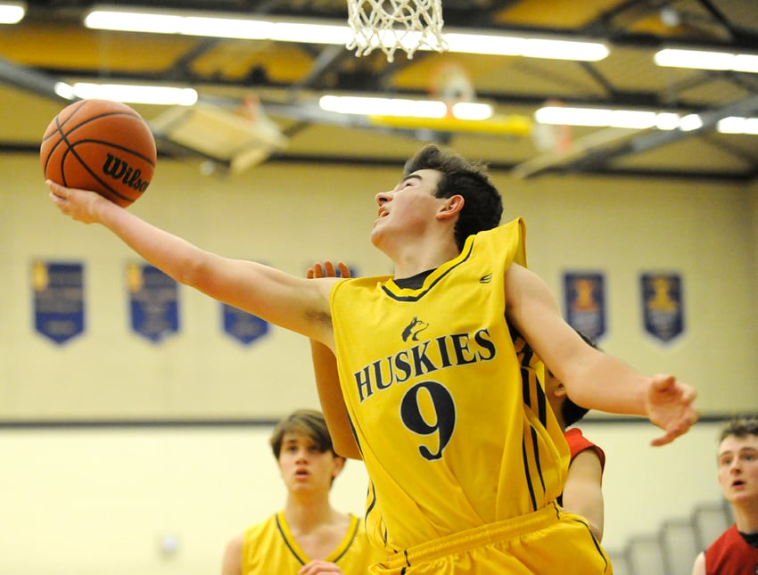 <who>Photo Credit: Lorne White/KelownaNow </who>OKM Huskies' Phil Michl goes up for a layup against the St. George's Saints in semifinal play at the KSS junior tournament.