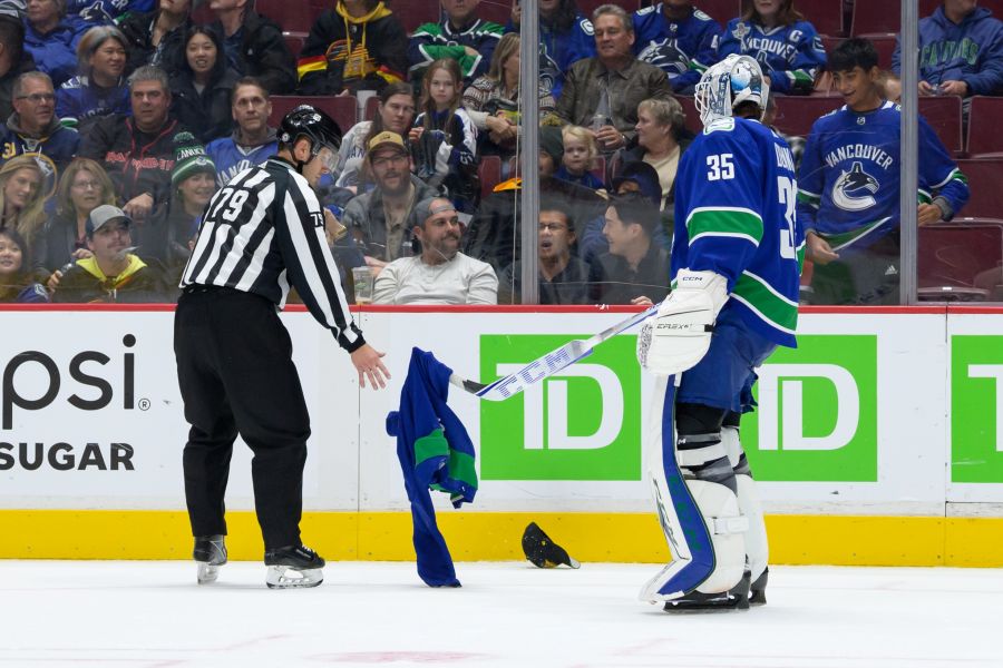 <who>Photo Credit: Getty Images</who>Canucks goalie Thatcher Demko scoops up a jersey thrown on the ice from a fan during the team's home opener in October.