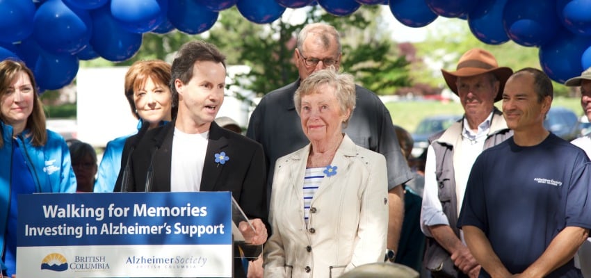 <who> Photo Credit: KelownaNow </who> Steve Bennett, with his mother Audrey Bennett by his side, speaks on behalf of his father, Bill Bennett, who lost his battle with Alzhemier's in December, 2015. 