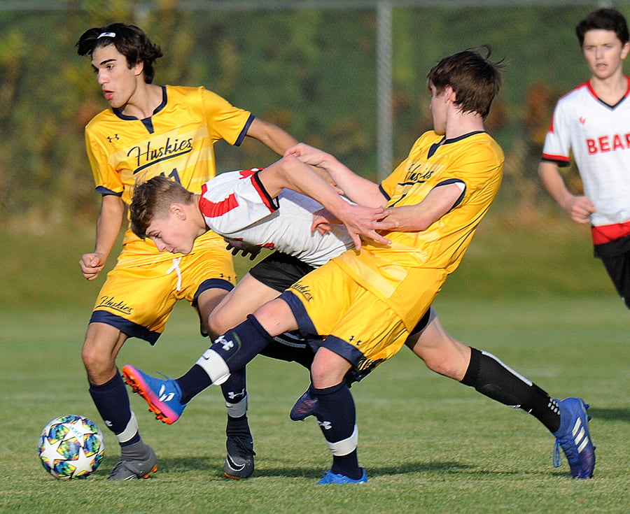 Boucherie's Josh Clancy tries to squeeze between the Huskies' Brandon Nemes, left, and Ethan Ramchuk.