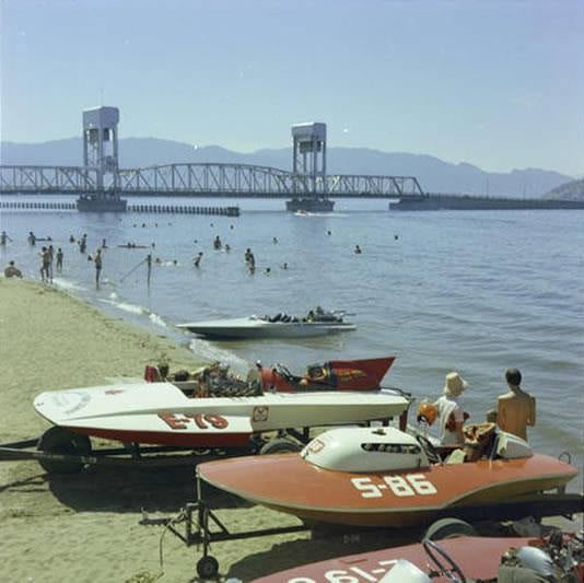 <who>Photo Credit: Old Kelowna/BC Archives</who>Today we race Sea-Doos and ride the wake on wakeboards, but all the rage at the Kelowna Regatta back in the 1970s, were hydroplane races. Regatta attendees watched from the shore as the hydroplanes soared across Okanagan Lake at the annual event. (Circa 1972)