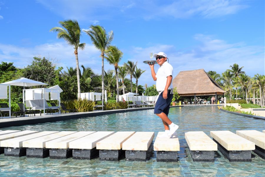 </who>Waiter Jesus walks across the pool at the Conrad Tulum Resort.