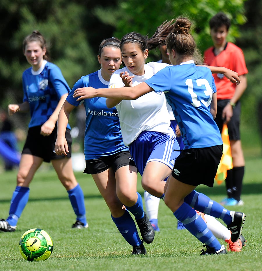 <who>Photo Credit: Lorne White/KelownaNow </who>West Kelowna's Abigail Taneda squeezes through a pair of Wave defenders to get to a loose ball.