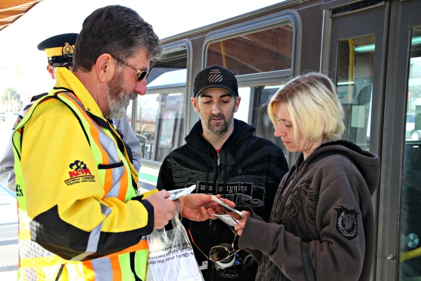 RCMP Volunteer Frank Stariha hands out reflective tape and information on pedestrian safety to transit users.