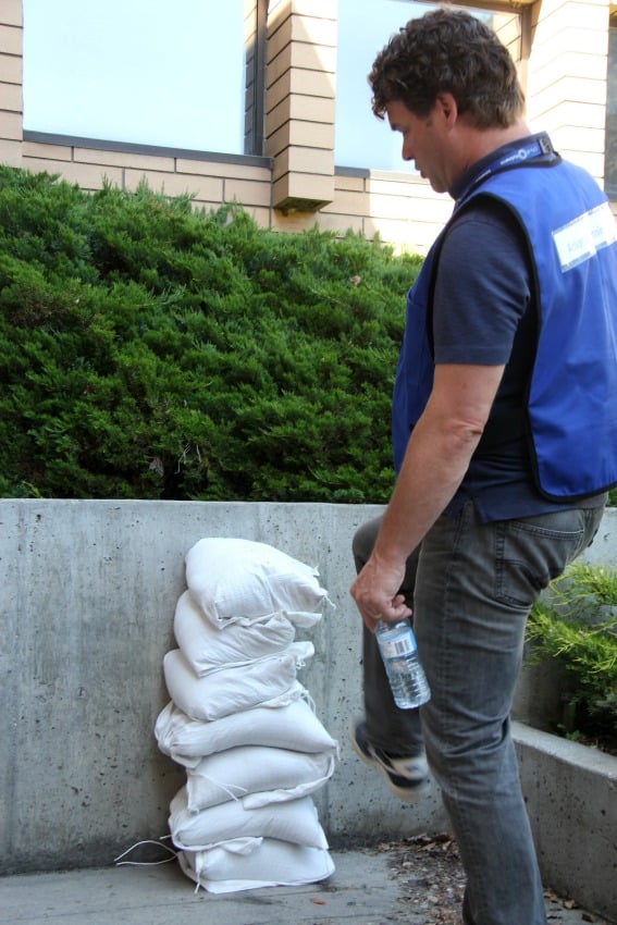 <who> Photo Credit: KelownaNow </who> Todd Cashin shows how easy it is to knock over a single-stacked sandbag wall.
