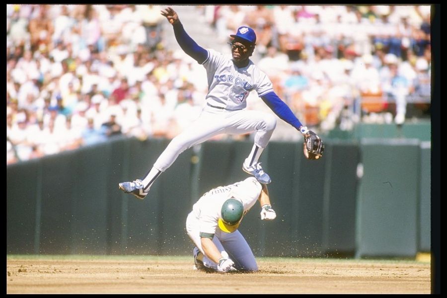 <who>Photo credit: Credit: Otto Greule /Allsport/Getty Images</who> Tony Fernandez of the Toronto Blue Jays leaps over first baseman Mark McGwire of the Oakland Athletics during a game of the 1989 American League Championship.