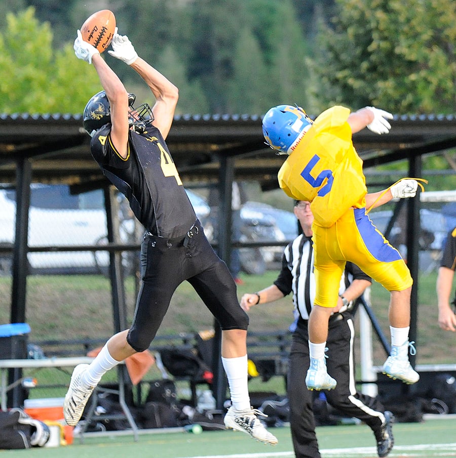 <who>Photo Credit: Lorne White/KelownaNow </who>Caeleb Schlachter leaps to grab an Isaac Athans pass over the outstretched arms of Rutland’s Ryan Dovedoff in the first quarter of their win over the Voodoos at CNC.
