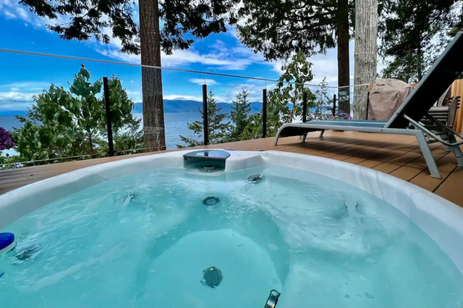 <who> Photo Credit: AirBnb </who> The expanded patio and hot tub, overlooking the Salish Sea. 