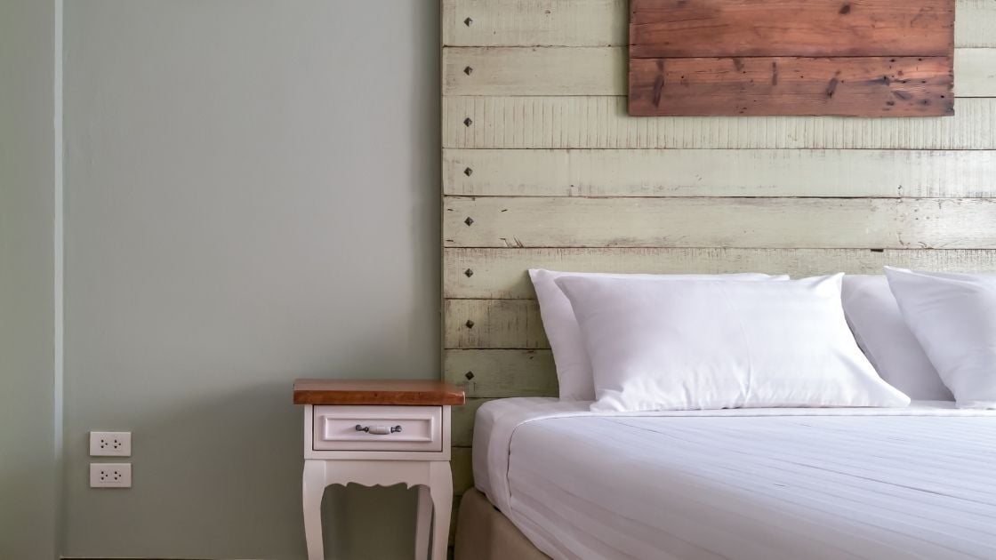 The white line and light walls are offset perfectly by the cream wood headboard.  The addition of the headboard accent matches the bedside table.