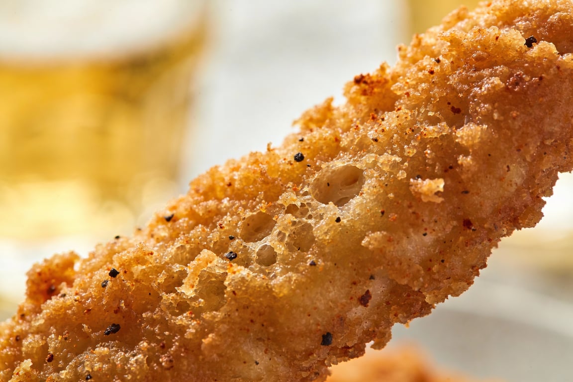 Amber Ale Beer-Battered Chicken Tenders being dipped into a bubbly batter