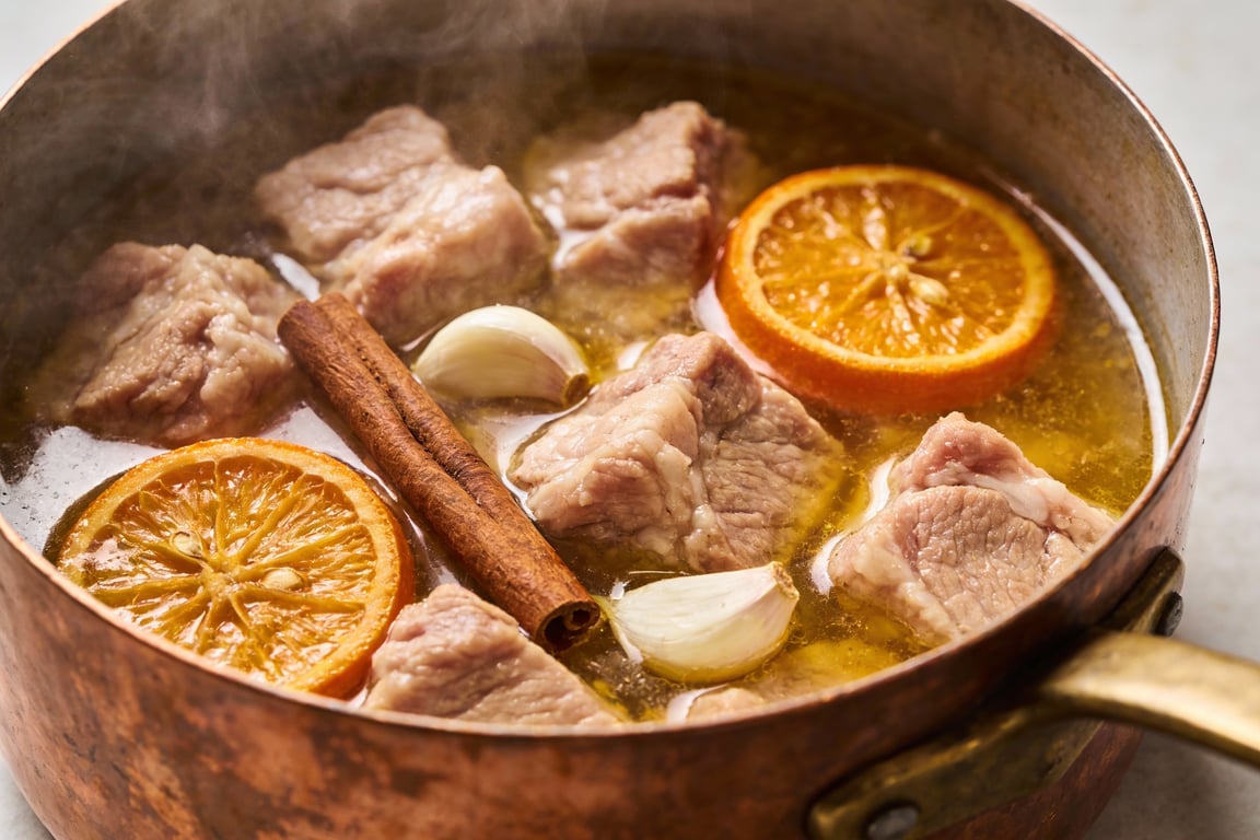 Authentic Mexican carnitas simmering in a Dutch oven