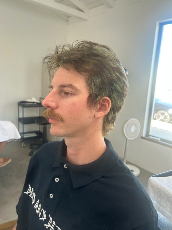 Styled hair with a subtle green tint and a well-groomed mustache.