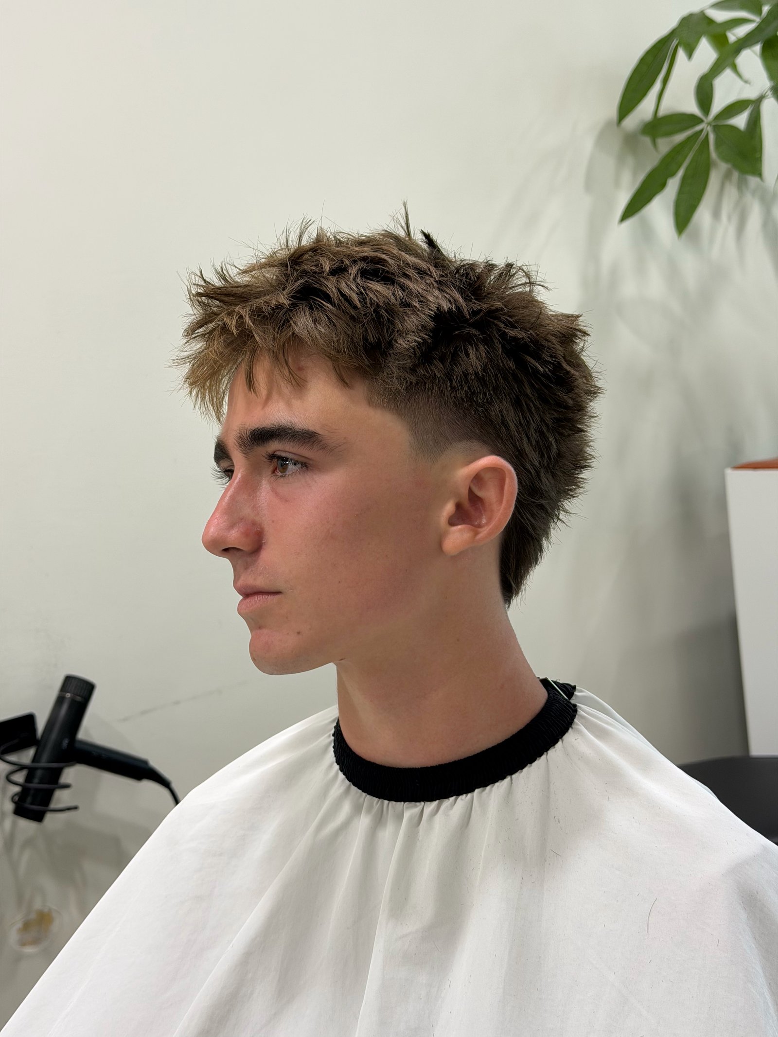 Textured hairstyle with a clean fade and defined shape.