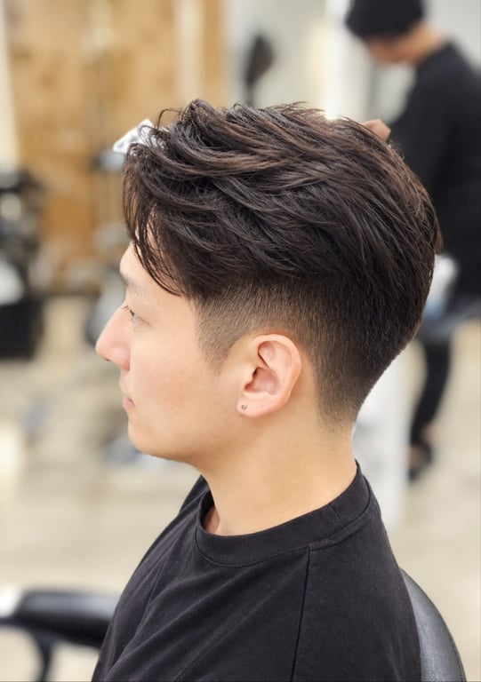 Stylish textured haircut with a clean fade and defined shape.