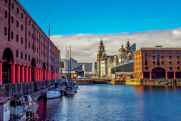 View of Albert Dock in Liverpool with moored boats and historic waterfront buildings.