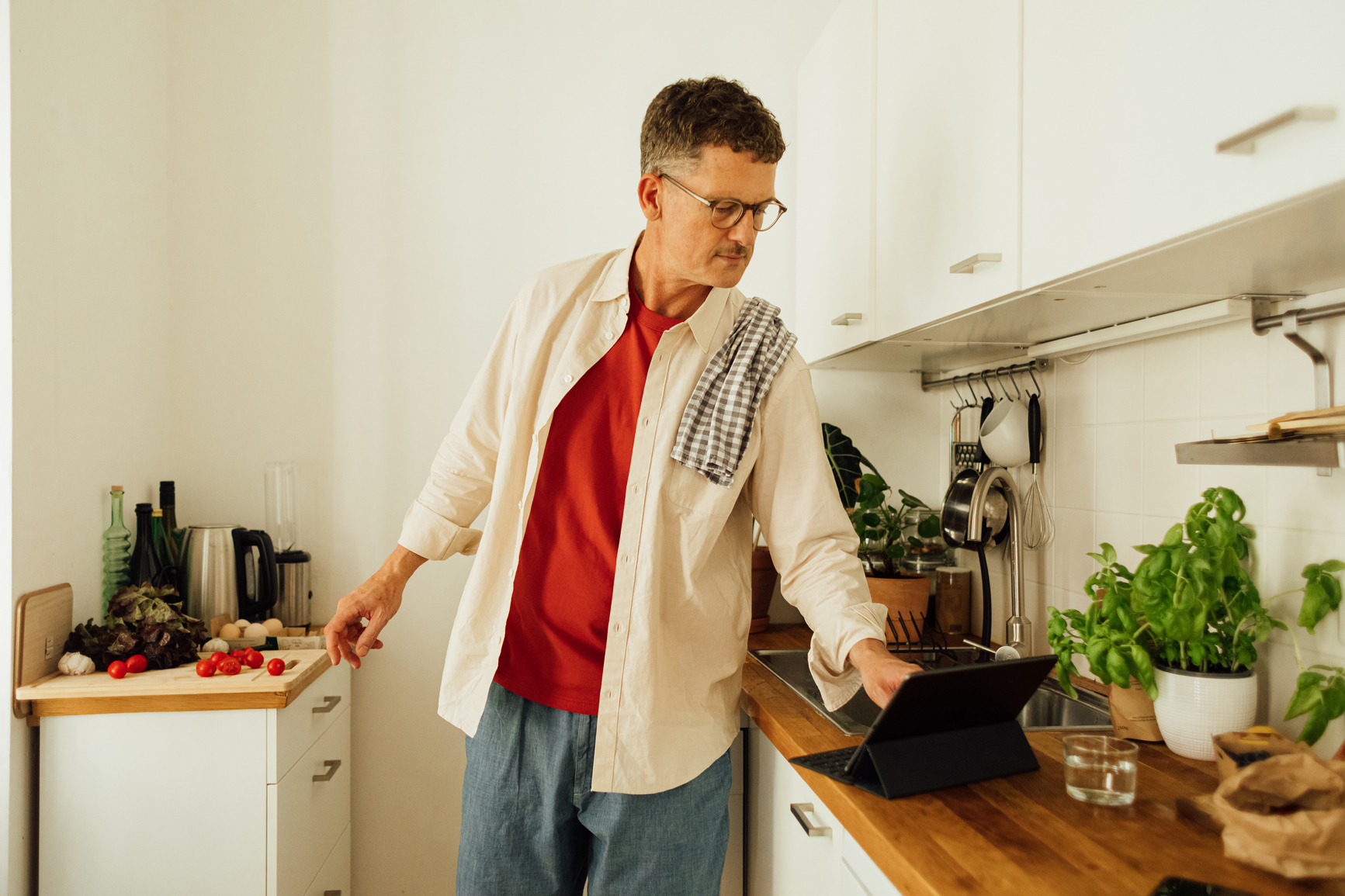 Man cooking in a kitchen, using an iPad for recipe
