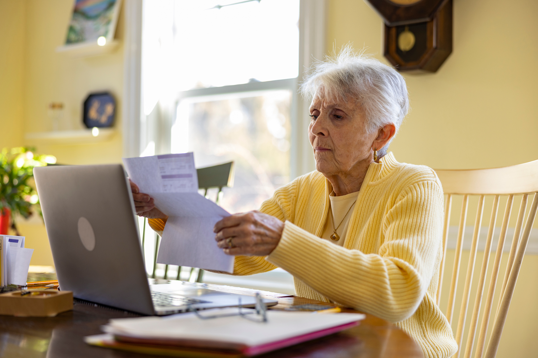 Woman reviewing documents beside a computer.