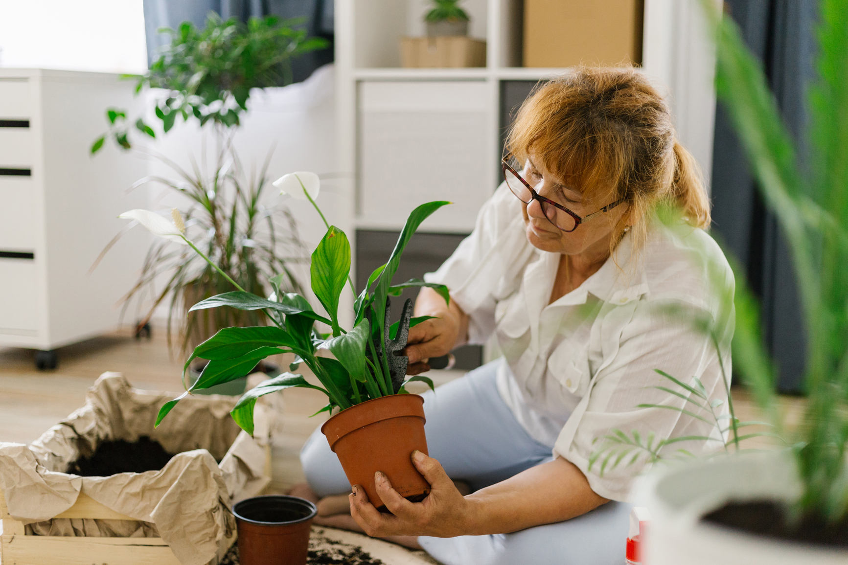 Person repotting a plant at a table with fresh soil.