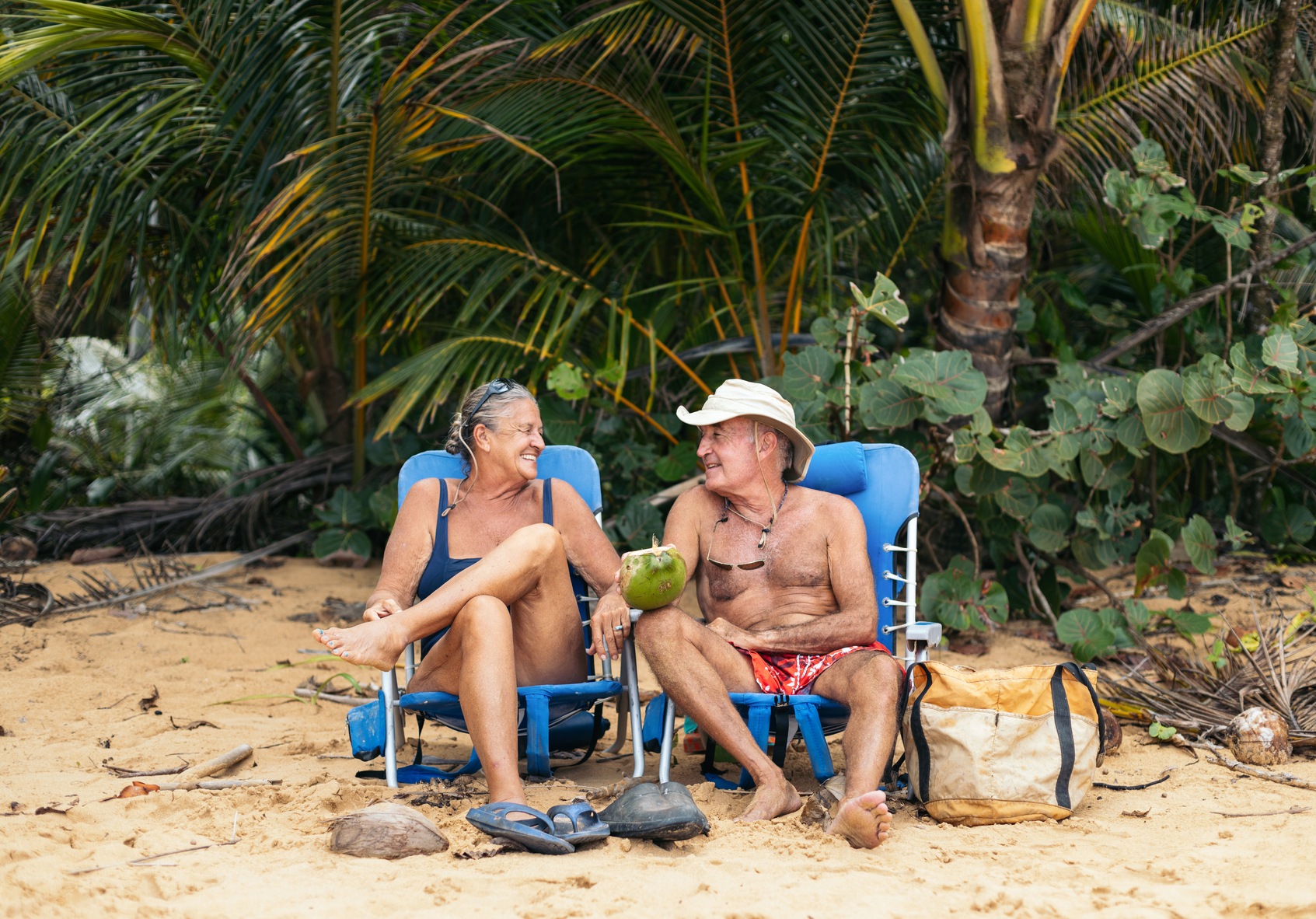 Senior couple sitting on a tropical beach in beach chairs