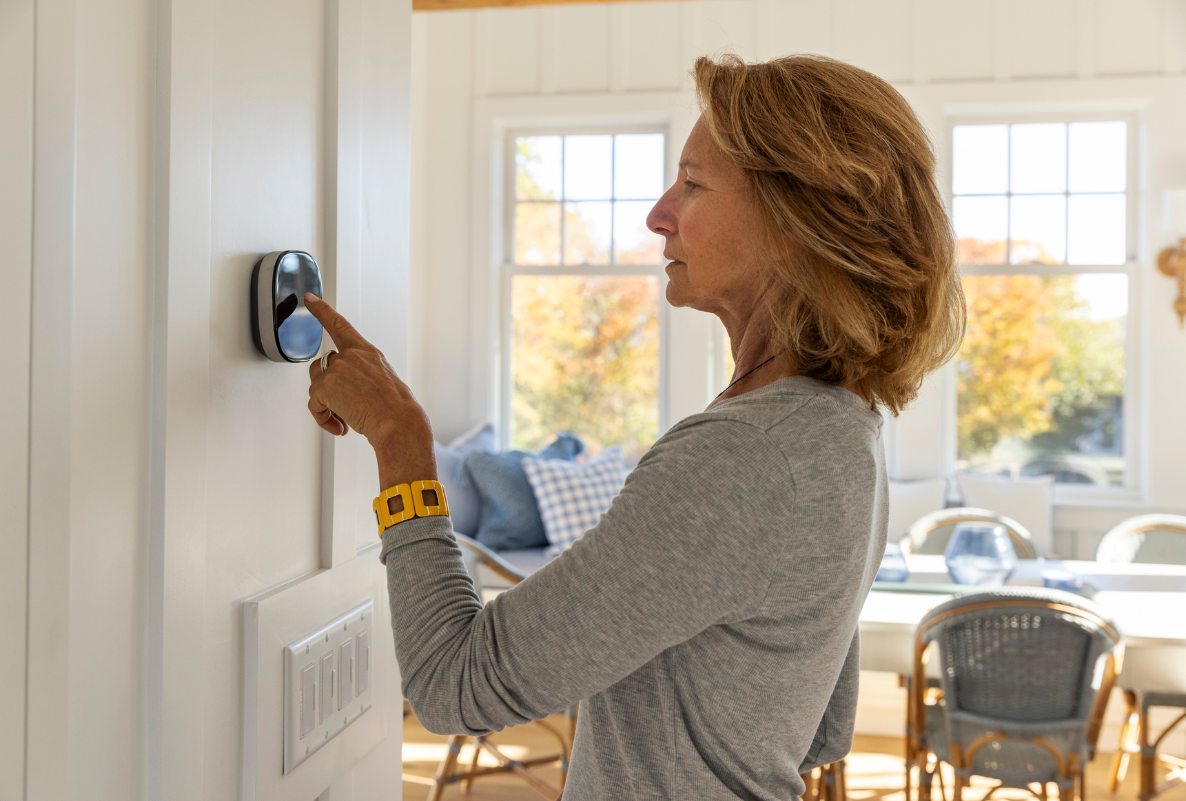Woman adjusting a smart thermostat.