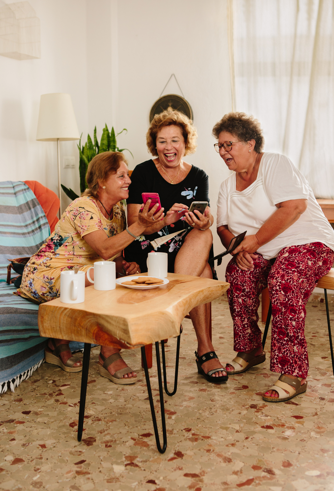 Friends laughing while looking at photos on their phones.