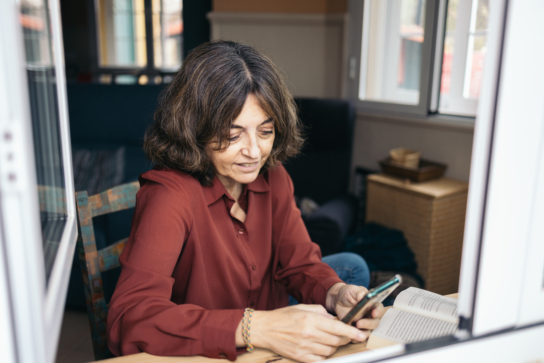 Person looking at a phone while reading a book.