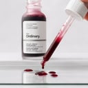 The Ordinary AHA BHA Peeling Solution red liquid droplets on glass surface