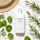 Skin1004 Tea-Trica Soothing Sun Milk on surface with sun and botanical elements