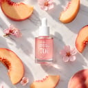 Anua Peach 70 Niacin Serum on surface with peach slices and botanical elements