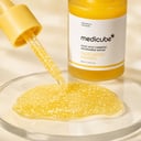 Medicube Kojic Acid Turmeric Serum droplets on glass with visible glow capsules