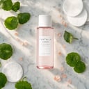 Skin1004 Poremizing Clear Toner on surface with cotton pads and pink salt