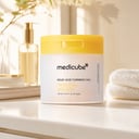 Medicube Kojic Acid Turmeric Pad jar on vanity with skincare products