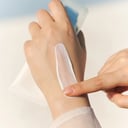Applying Skin1004 Centella Sun Serum on back of hand - dewy no white cast