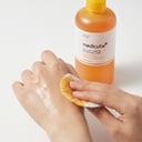 Applying Medicube Kojic Acid Turmeric Toner with cotton pad on hand