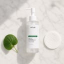 Anua Heartleaf Cleansing Oil Mild on surface with green leaf elements