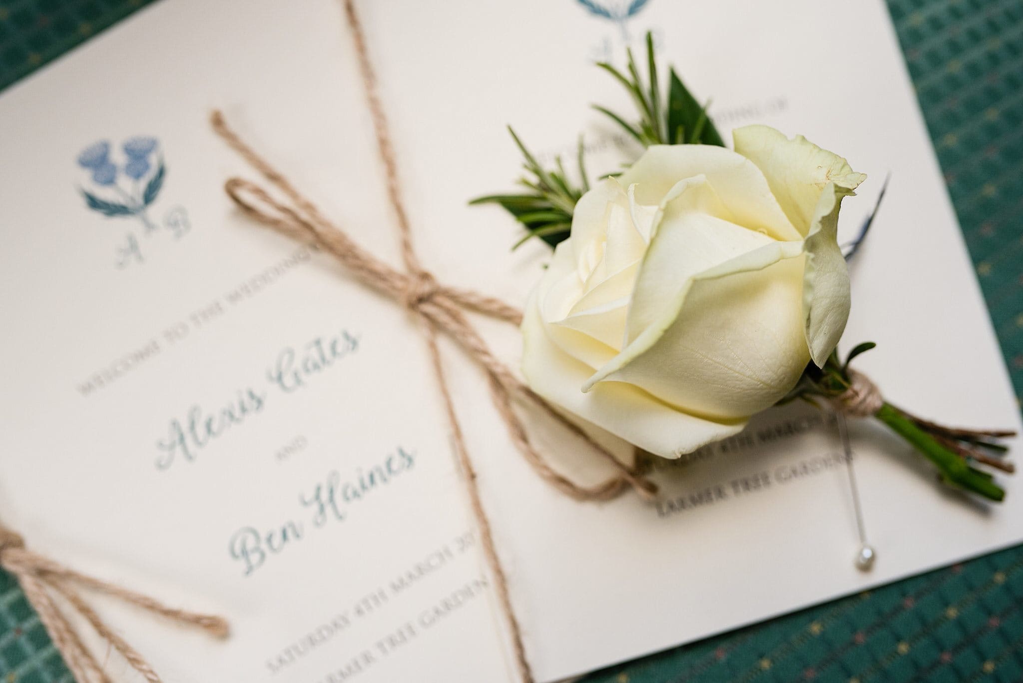 Rose rests on the wedding stationery - Larmertree Gardens wedding