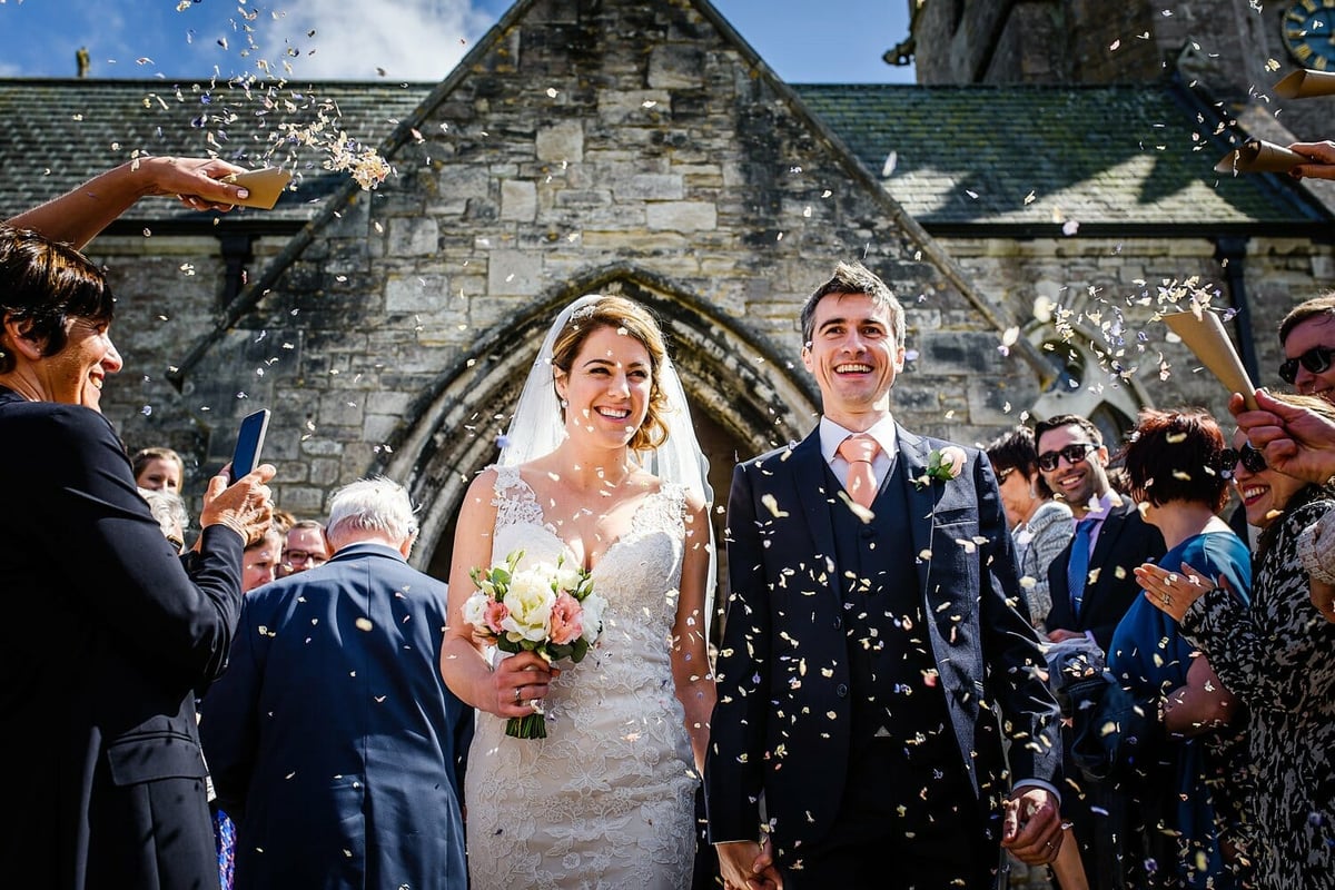 Bride and groom walk through Confetti