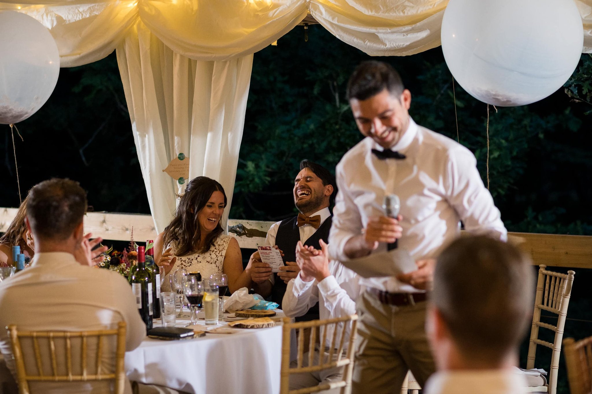 Bride and groom laugh at speech at Weddings in the Wood in Hampshire