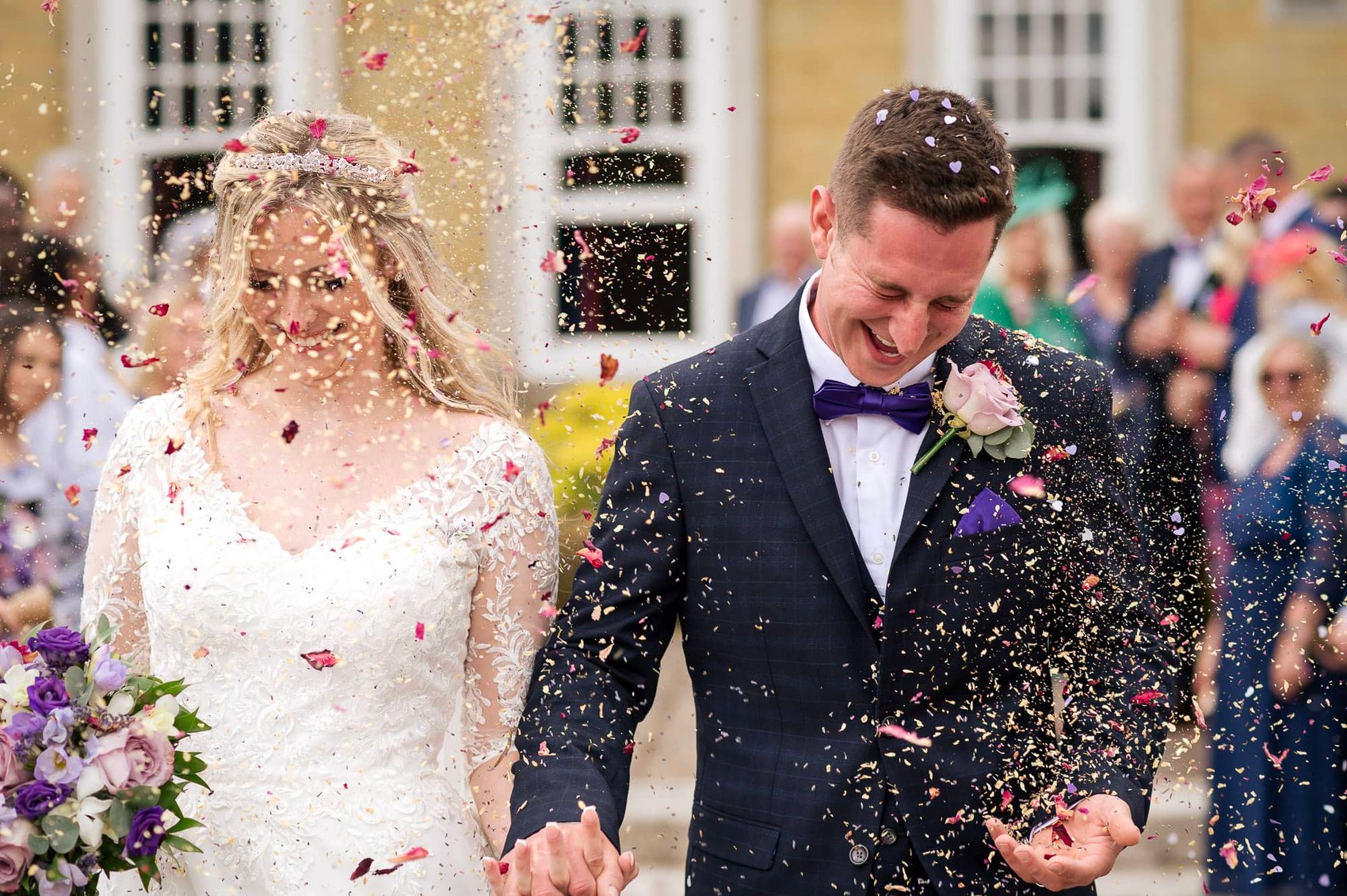 Bride and groom get a face full of confetti at their Chilworth Manor Hotel wedding