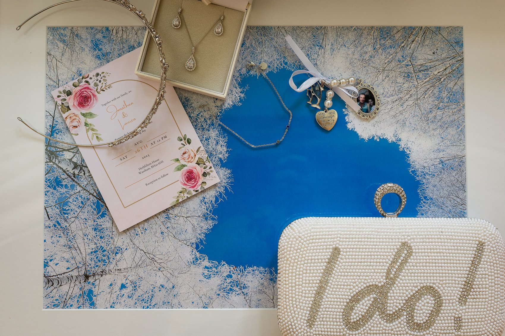Bridal details containing jewlery, invite and purse saying I do