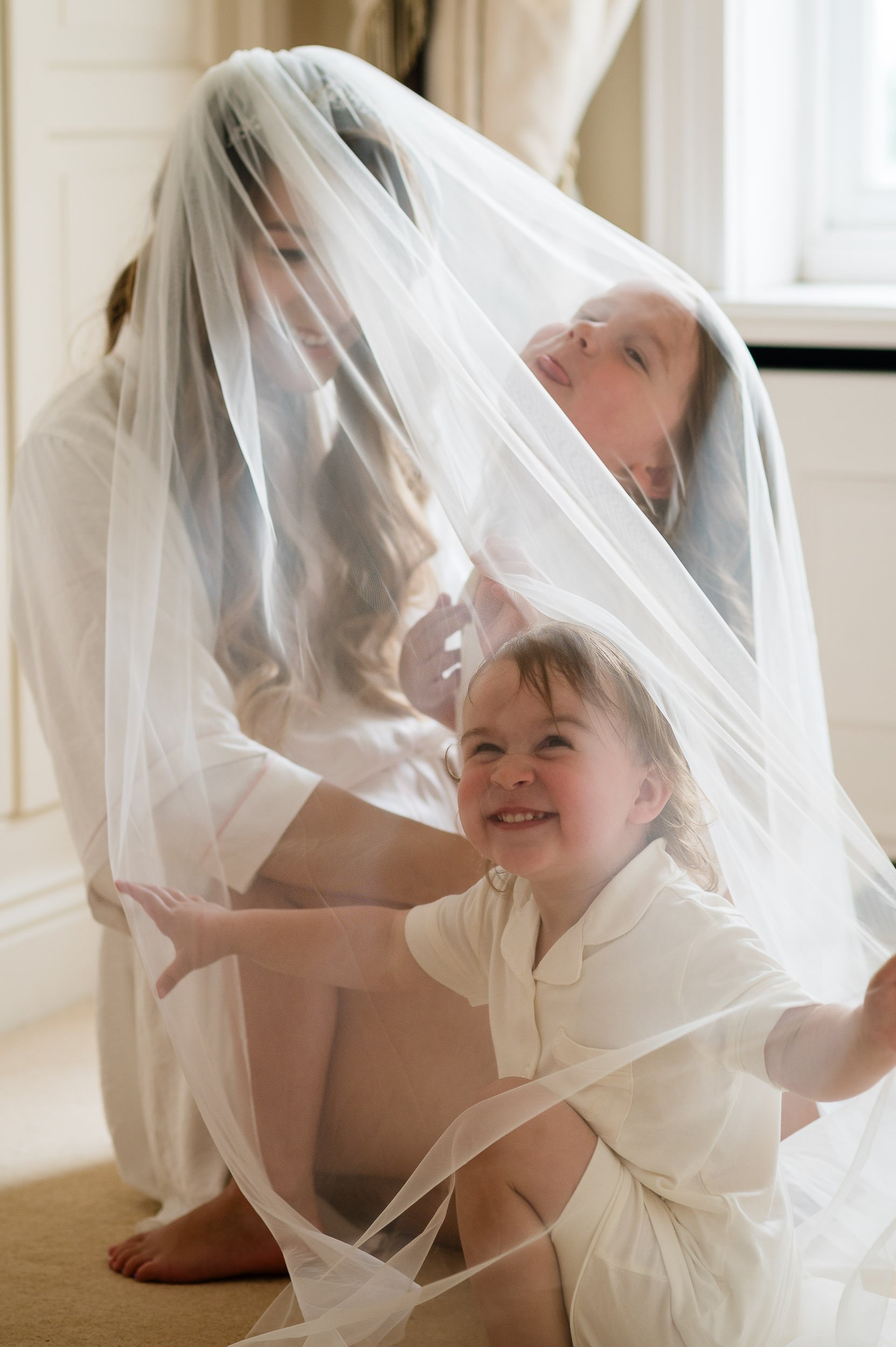 bride and her two daughters having fun under the wedding veil at Hethfelton House wedding
