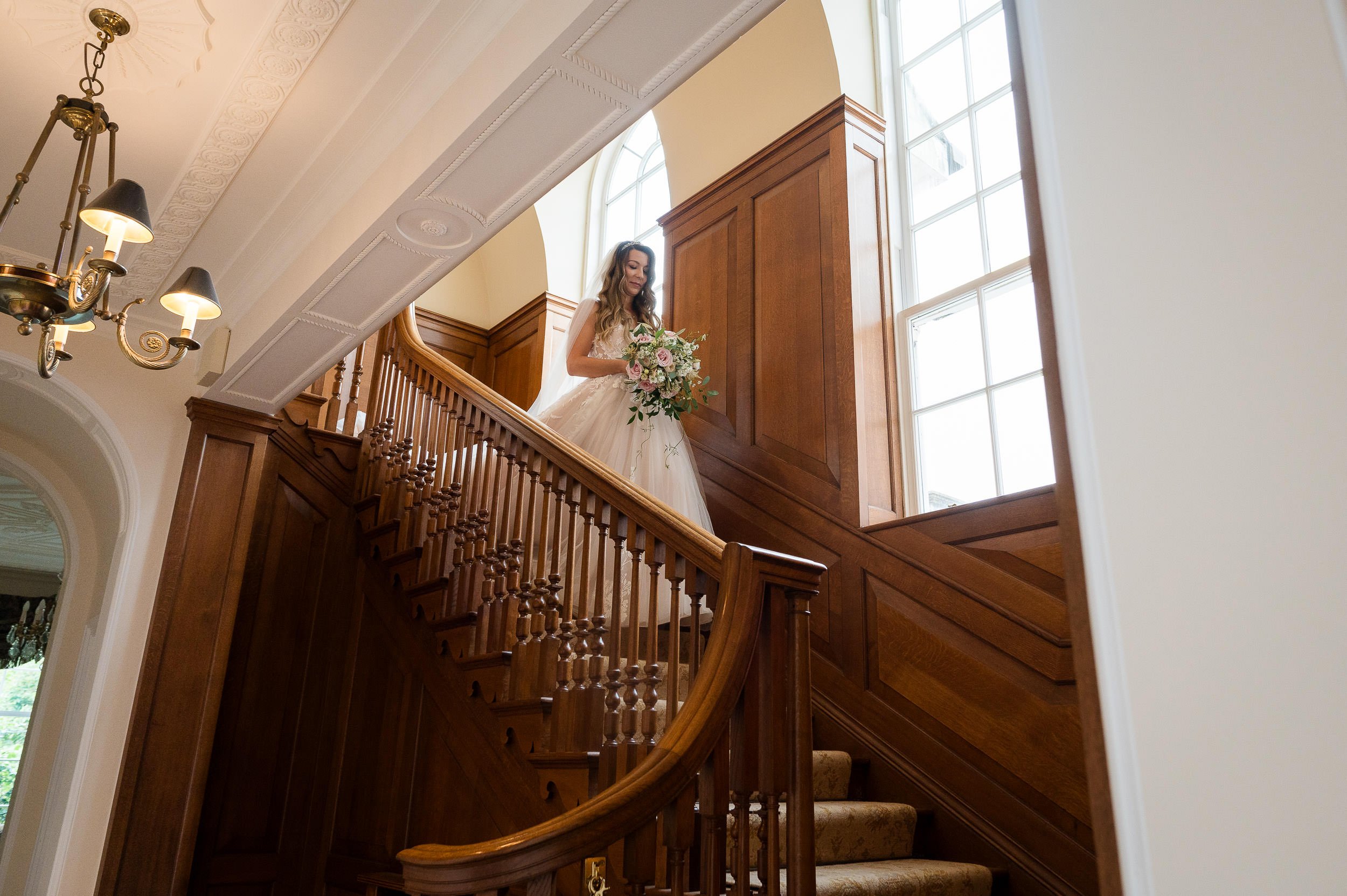 bride coming down the stairs at Hethfelton House wedding holding a bouquet