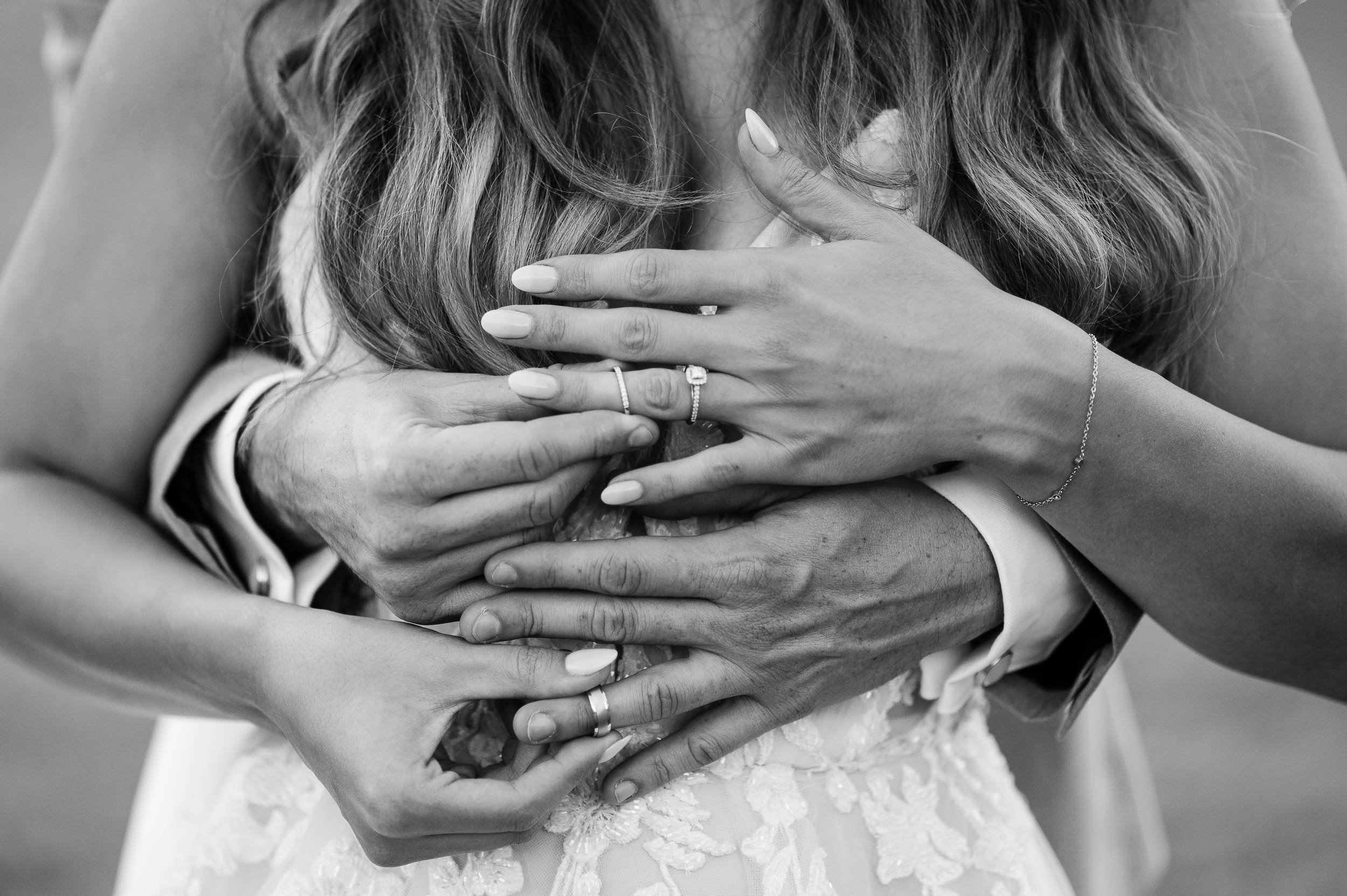 bride and grooms hands putting on their wedding rings in black and white