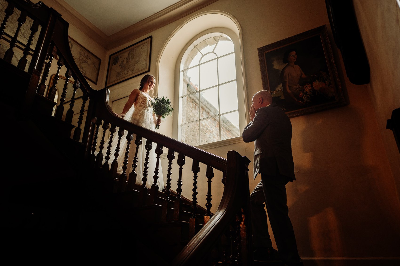 Dorset Wedding photographer watches Father of the Bride see his daughter on the stairs of Smedmore House