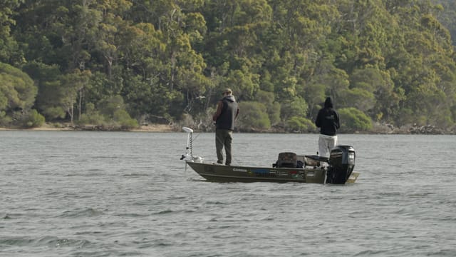 Two anglers drifting the chop in a camo tinny