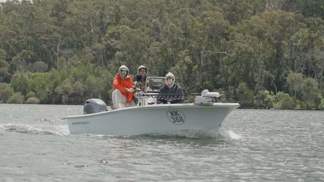 Three anglers motoring past a wall of eucalypt forest