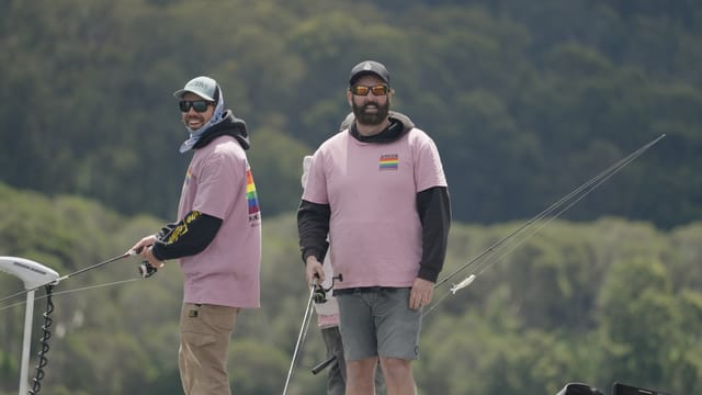 Teammates in matching team shirts, rods in hand