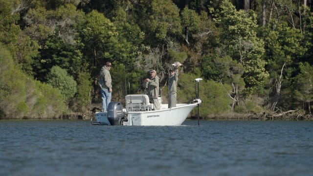 A crew holds up the catch mid-river